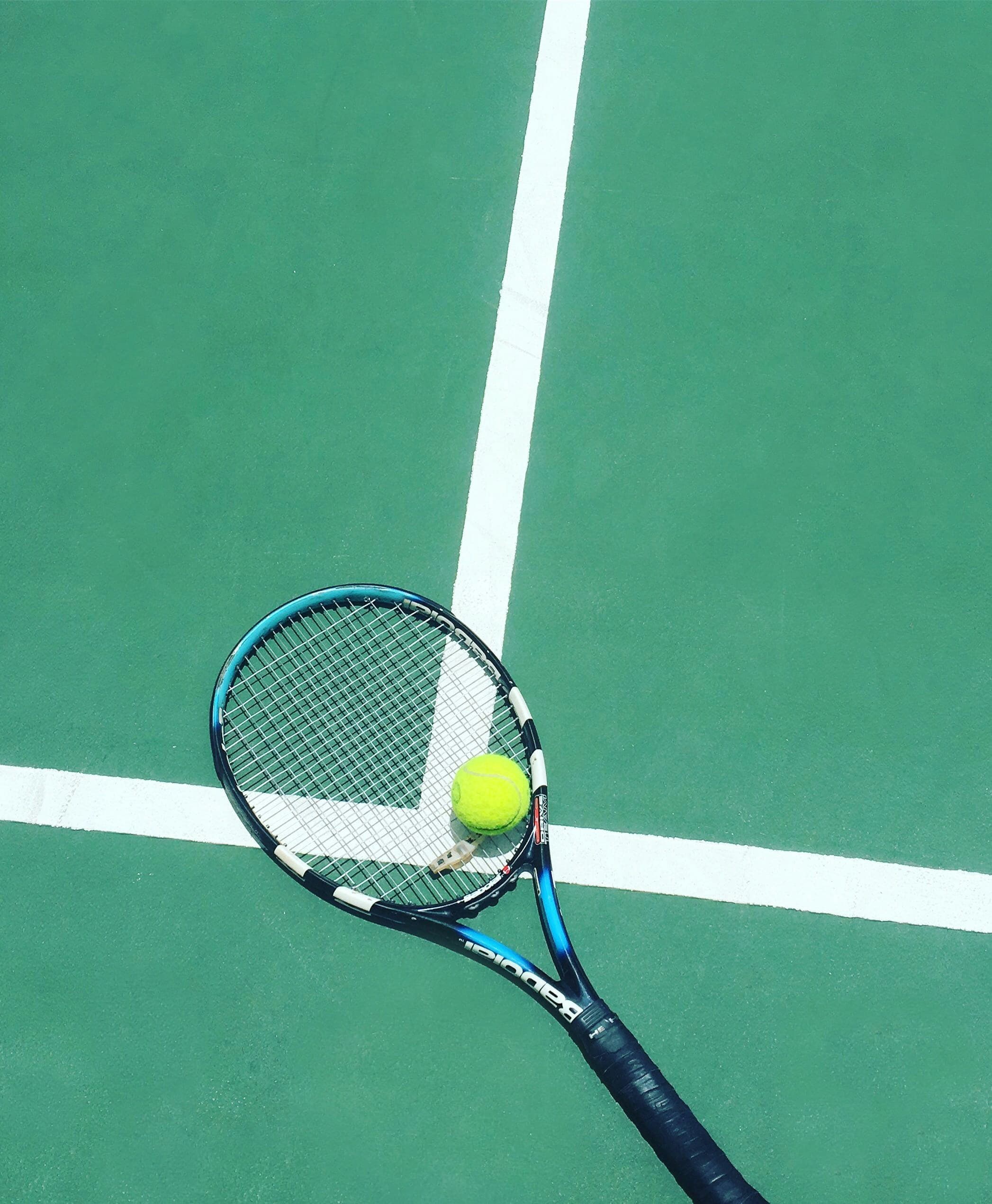 Tennis racket and ball on a green hard court